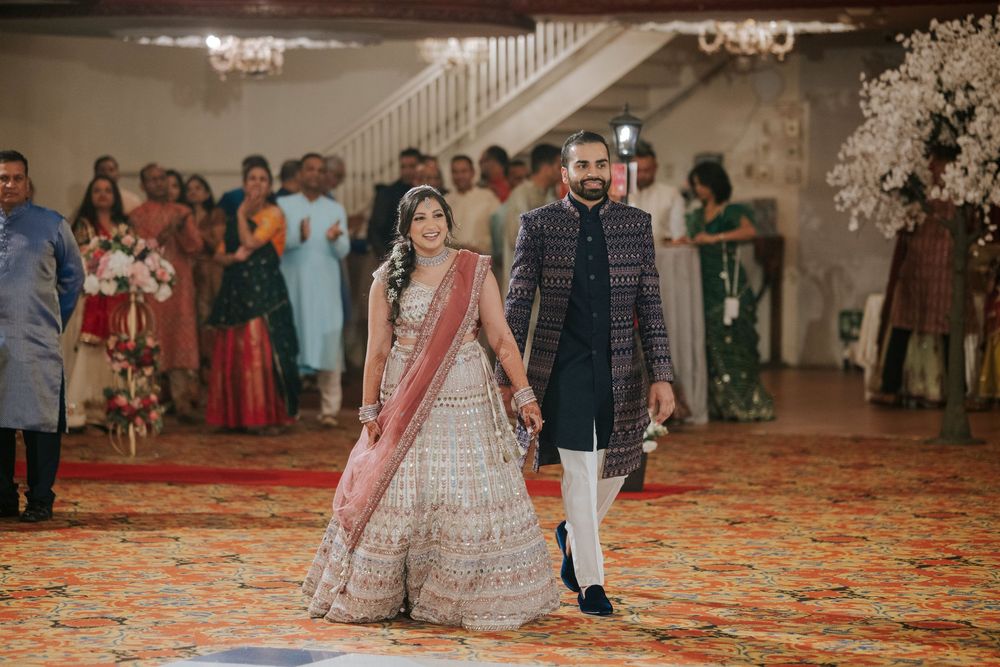 Couple dancing together at an elegant wedding reception in a grand ballroom with decorative lighting.