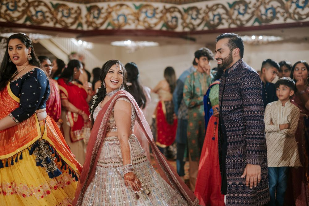 Guests dance and celebrate at a vibrant Indian wedding reception with colorful traditional outfits and decorations.