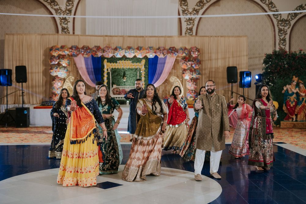 Festive dancers in colorful traditional Indian attire perform choreographed moves at an elegant ballroom reception.