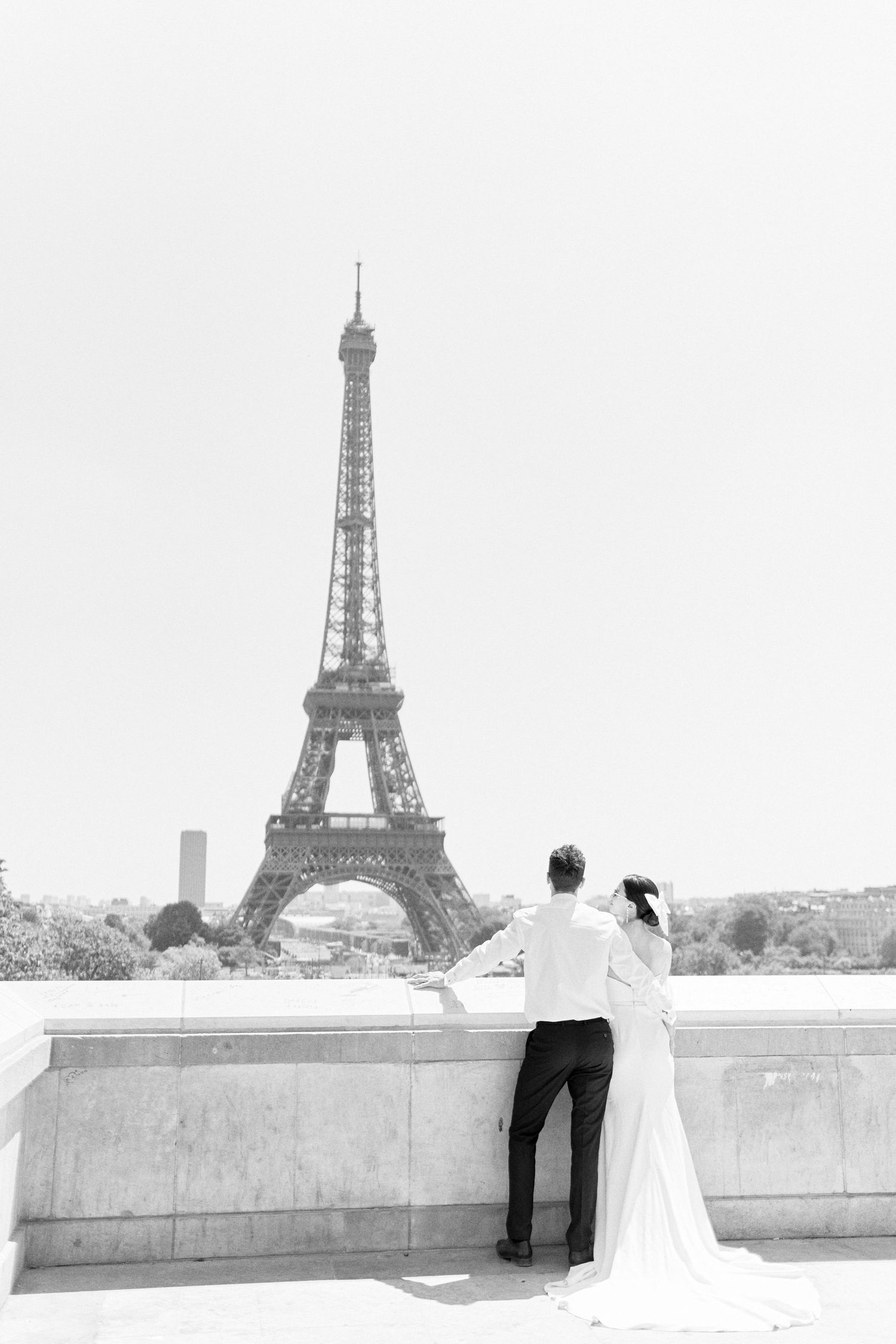 Paris wedding photographer captures a romantic photo of a bride and groom outside the iconic Eiffel Tower in Paris, France