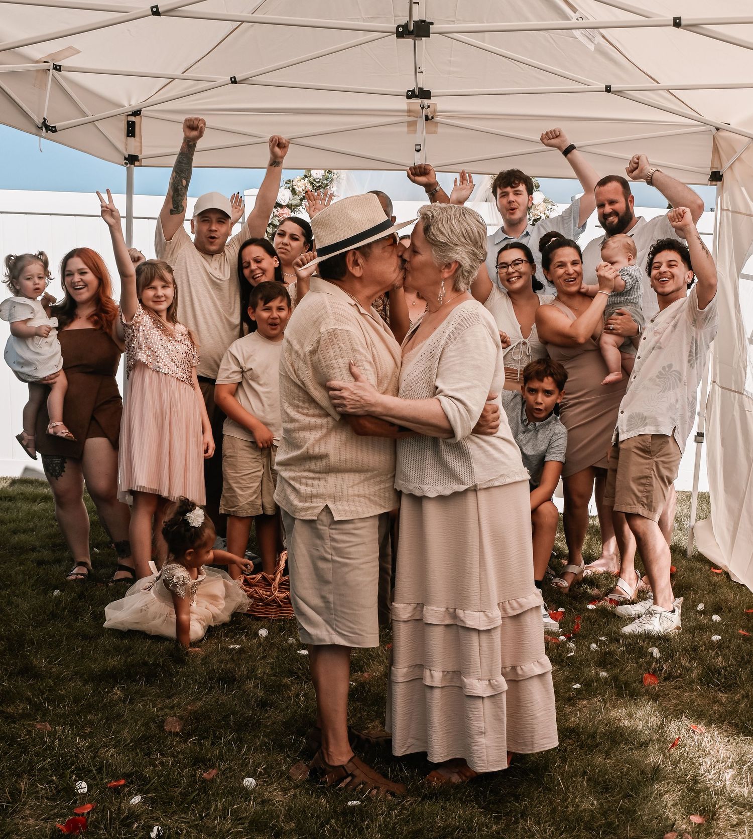 A joyful moment shared under a white tent canopy as guests celebrate during a warm outdoor gathering.