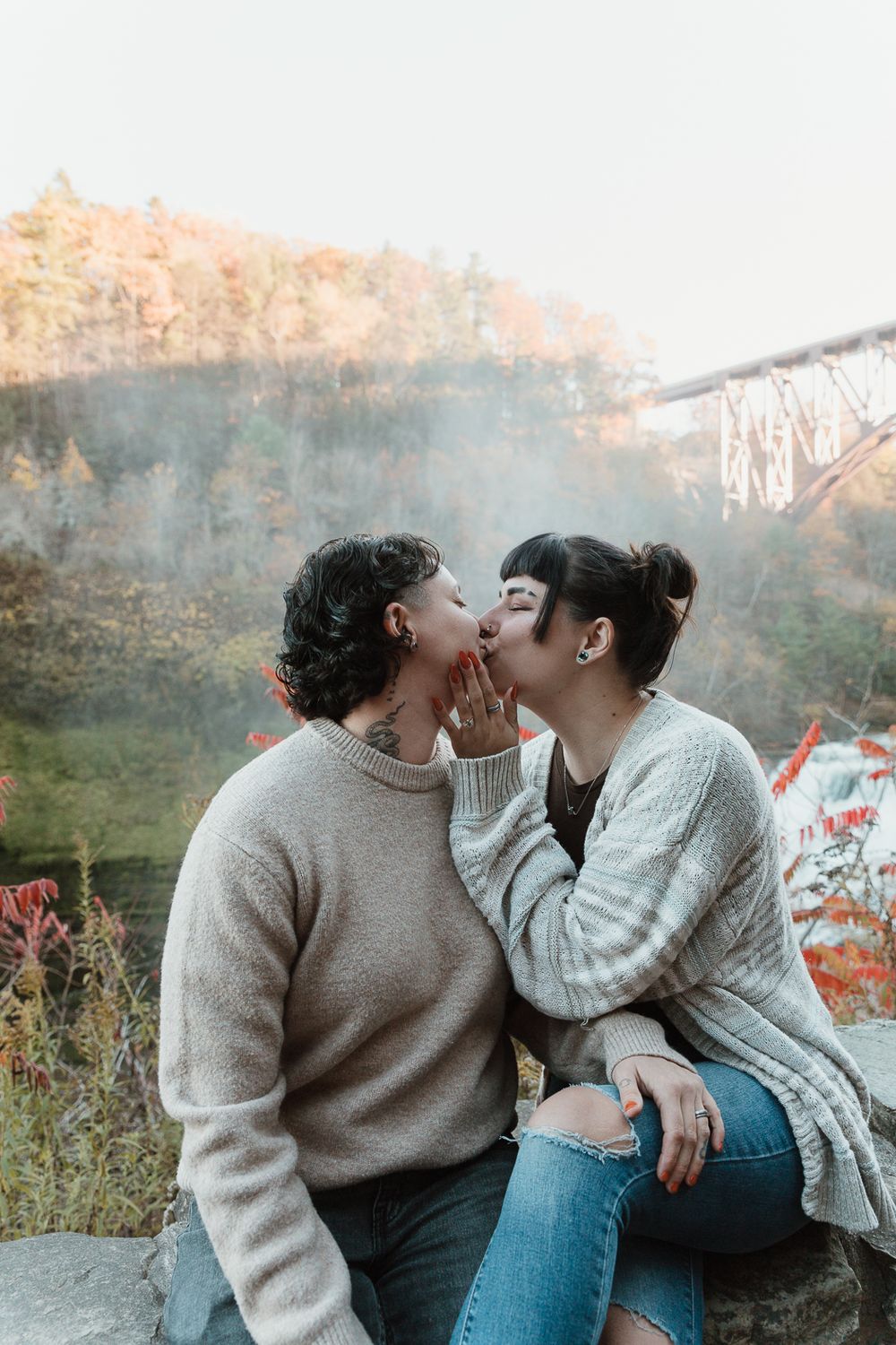 Two people in cozy sweaters share intimate moments outdoors during autumn at sunset.