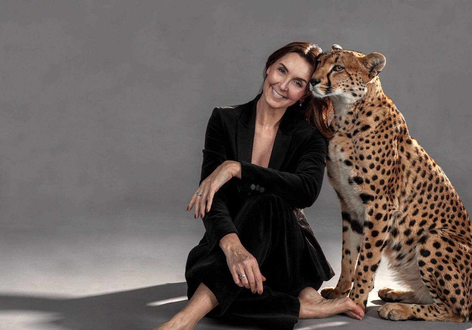 A series of black and white fashion photographs showing someone in dark clothing posing with a cheetah against a gray backdrop.