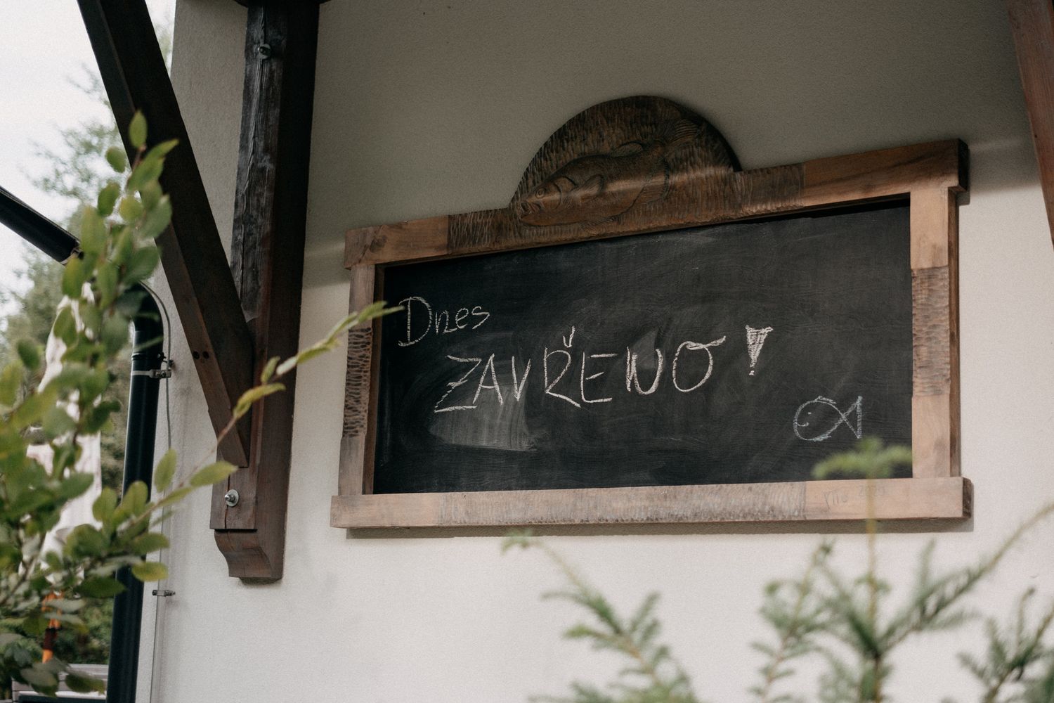 Rustic wooden chalkboard signs displayed at an outdoor wedding venue with trees in background.