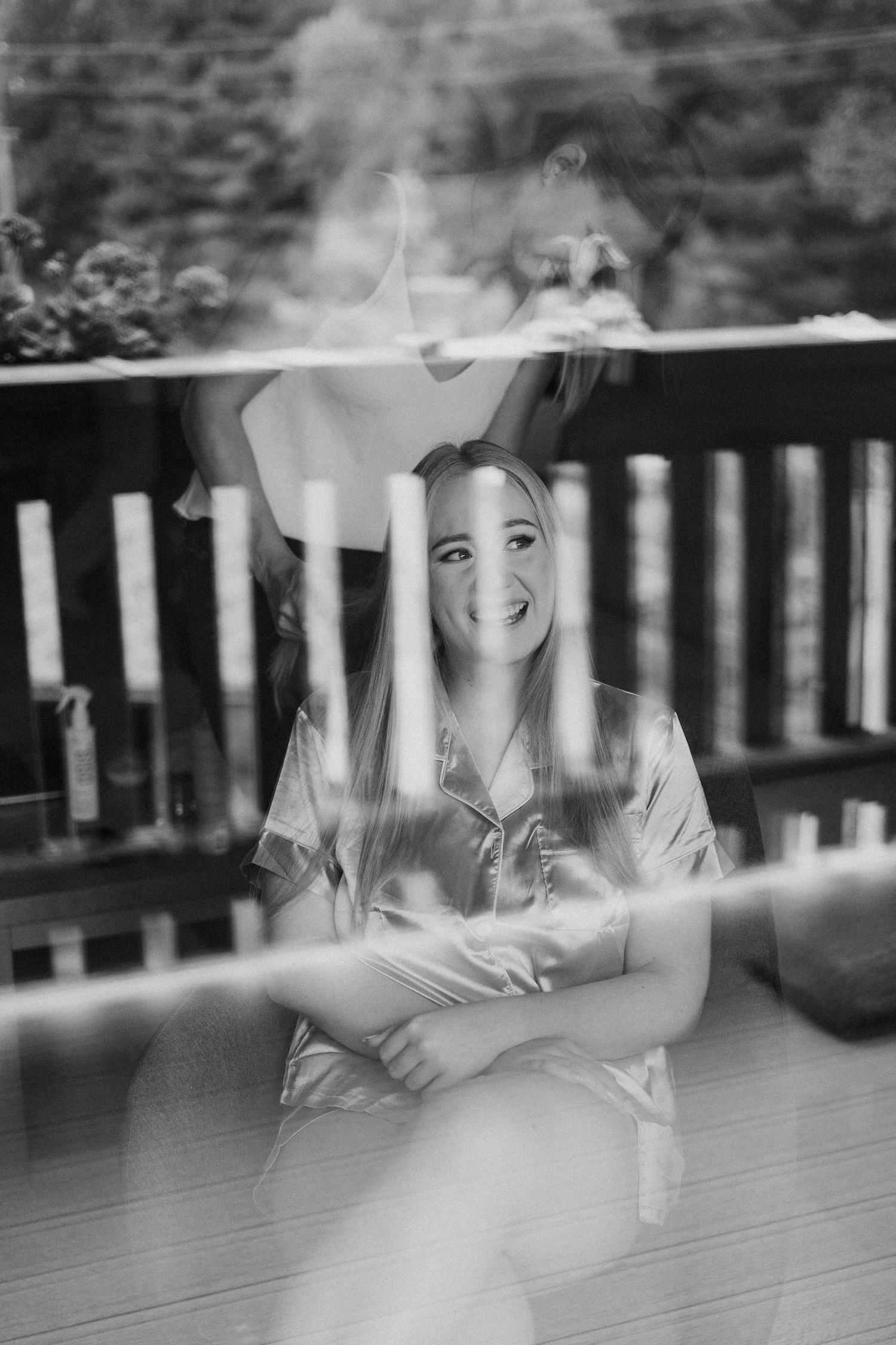 Black and white photo showing reflections in window panes with a rustic railing.