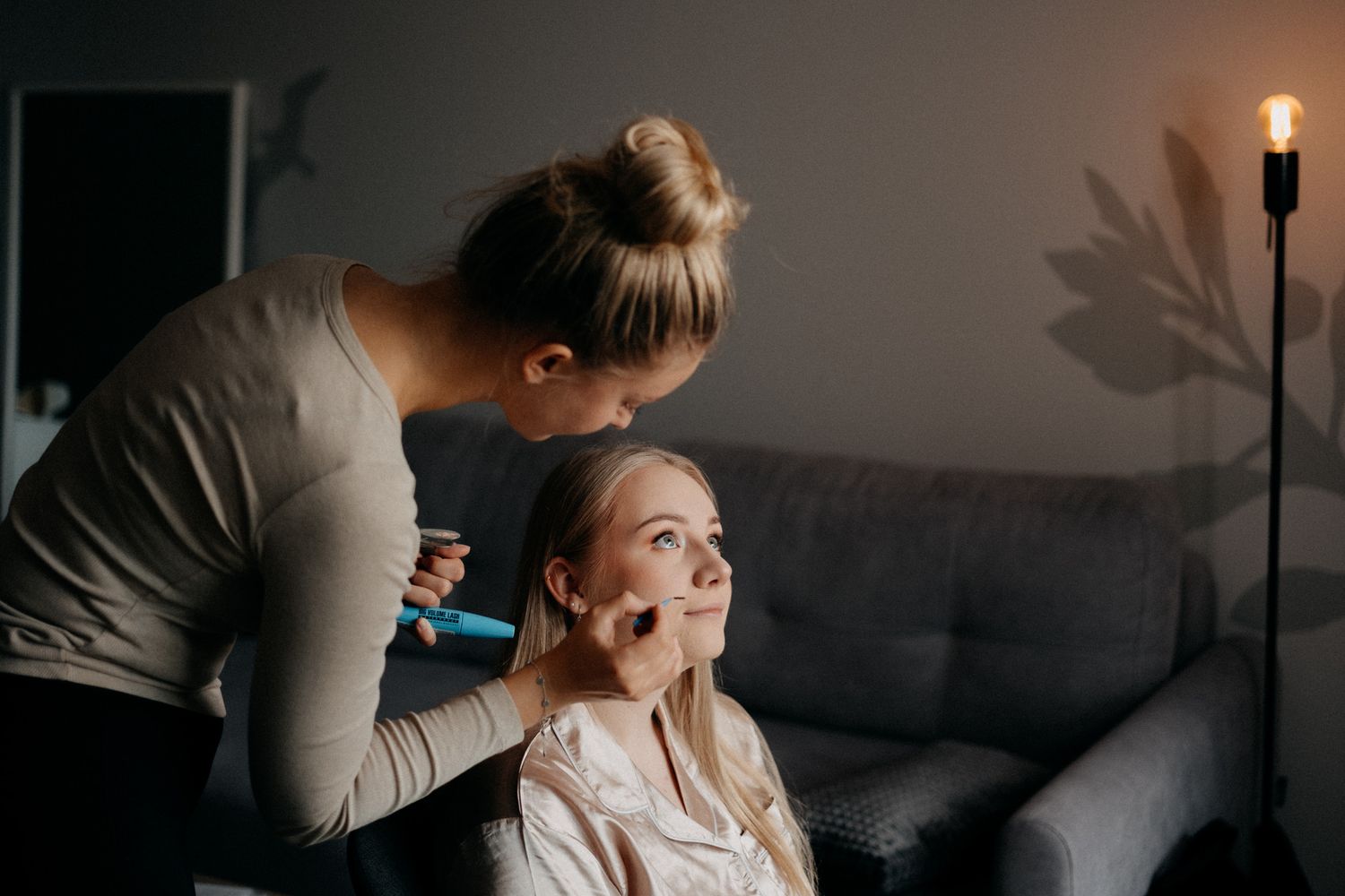 Makeup application session in dim room with warm lighting.