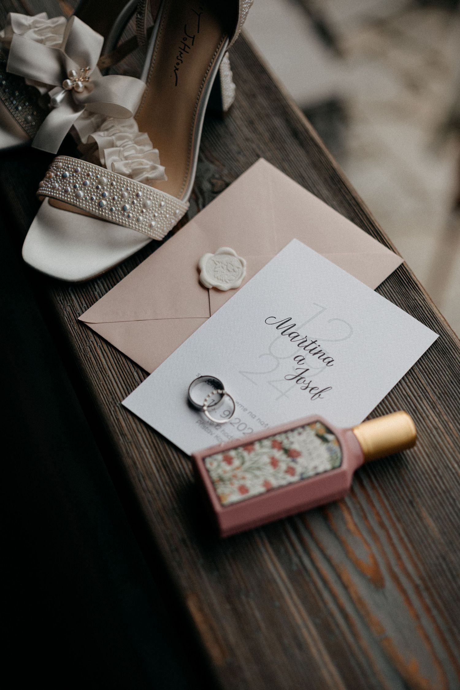 Wedding stationery and rings arranged artistically on rustic wooden surface in sepia tones.