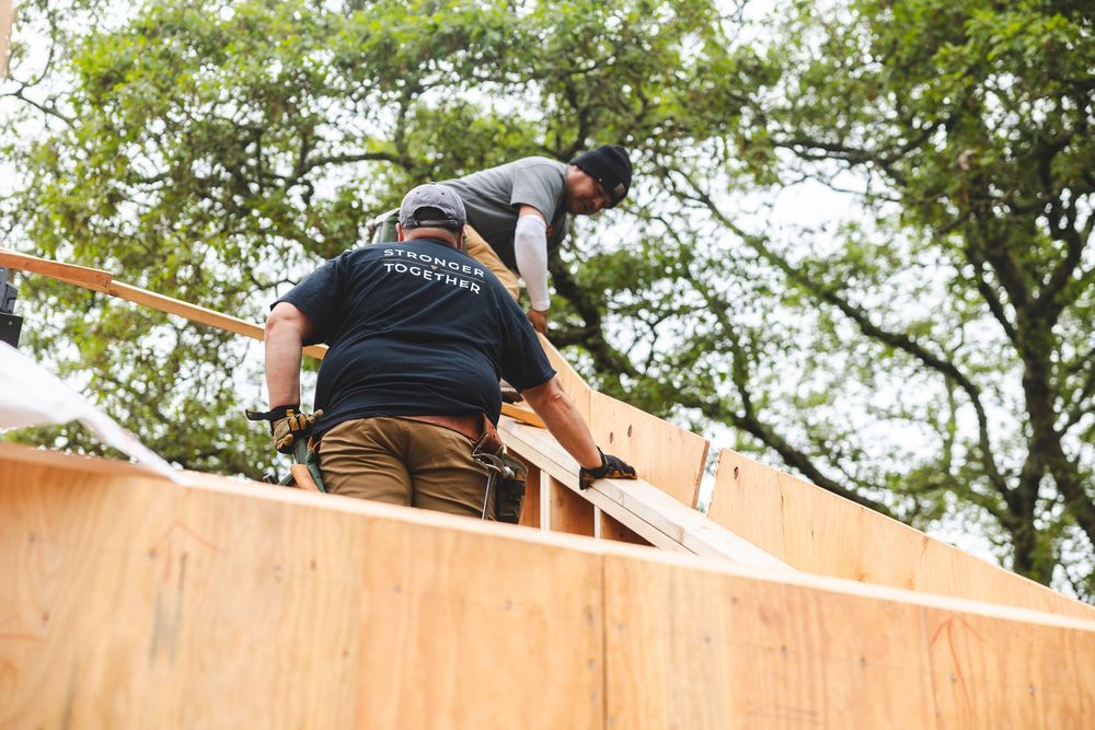 Construction crew member working on wooden roof structure during outdoor building project.