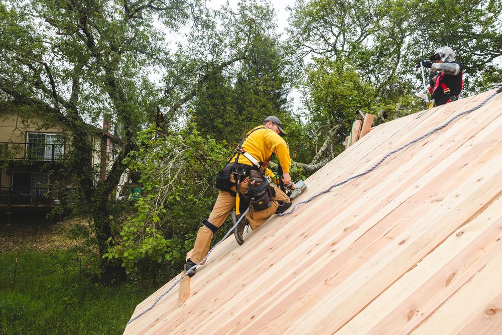 Workers installing plywood sheathing on the roof of a residential construction project.