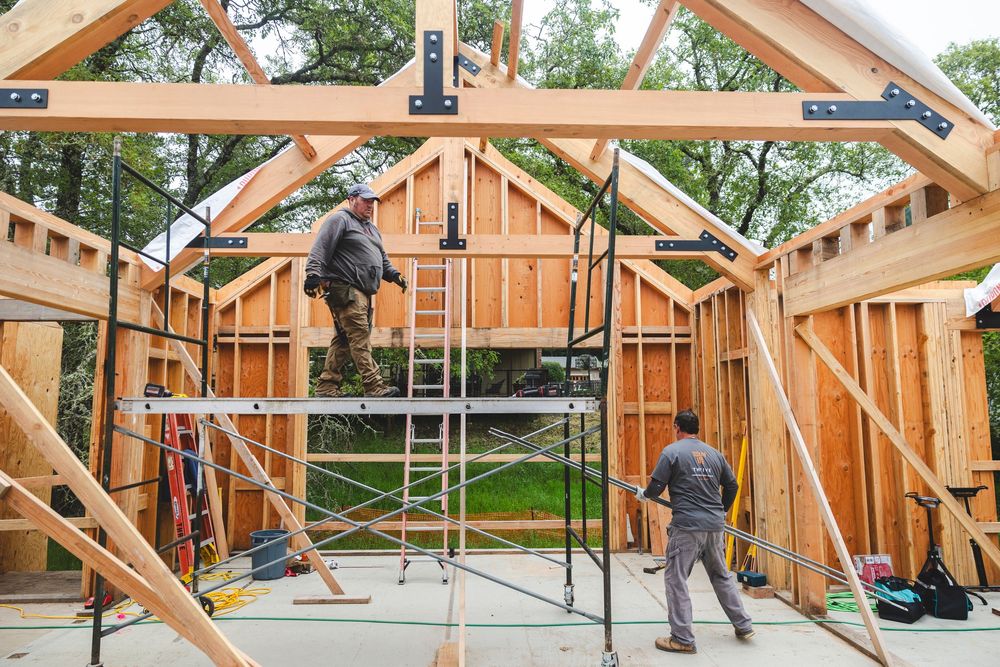 Construction workers installing wooden roof trusses on a new home build.