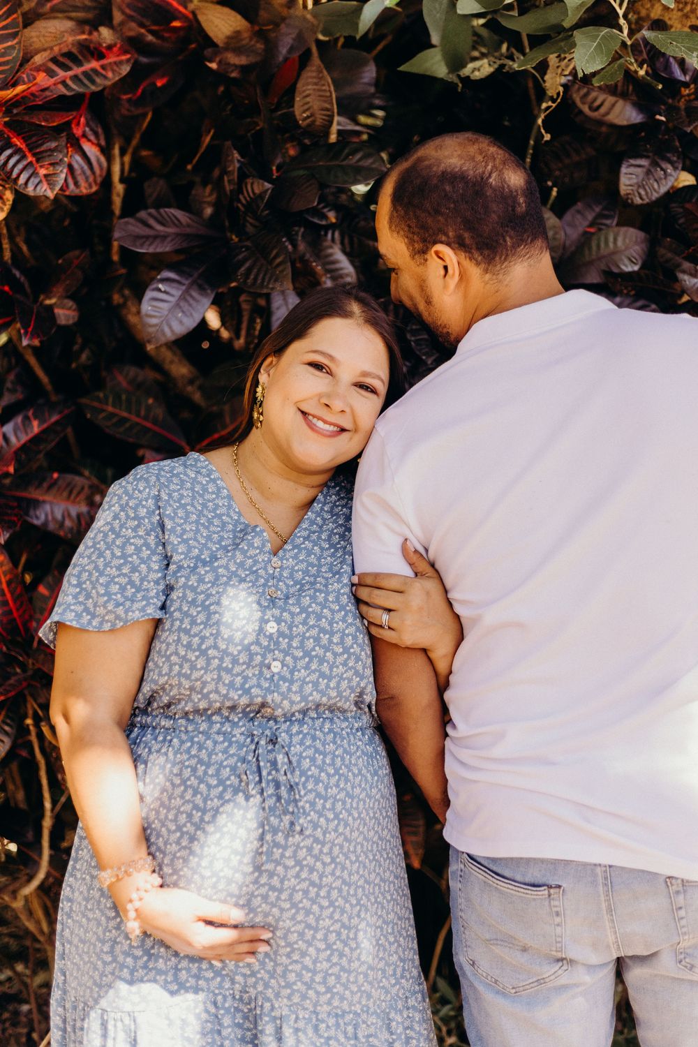 A couple shares intimate moments in a garden setting wearing blue polka dot dress and white shirt.