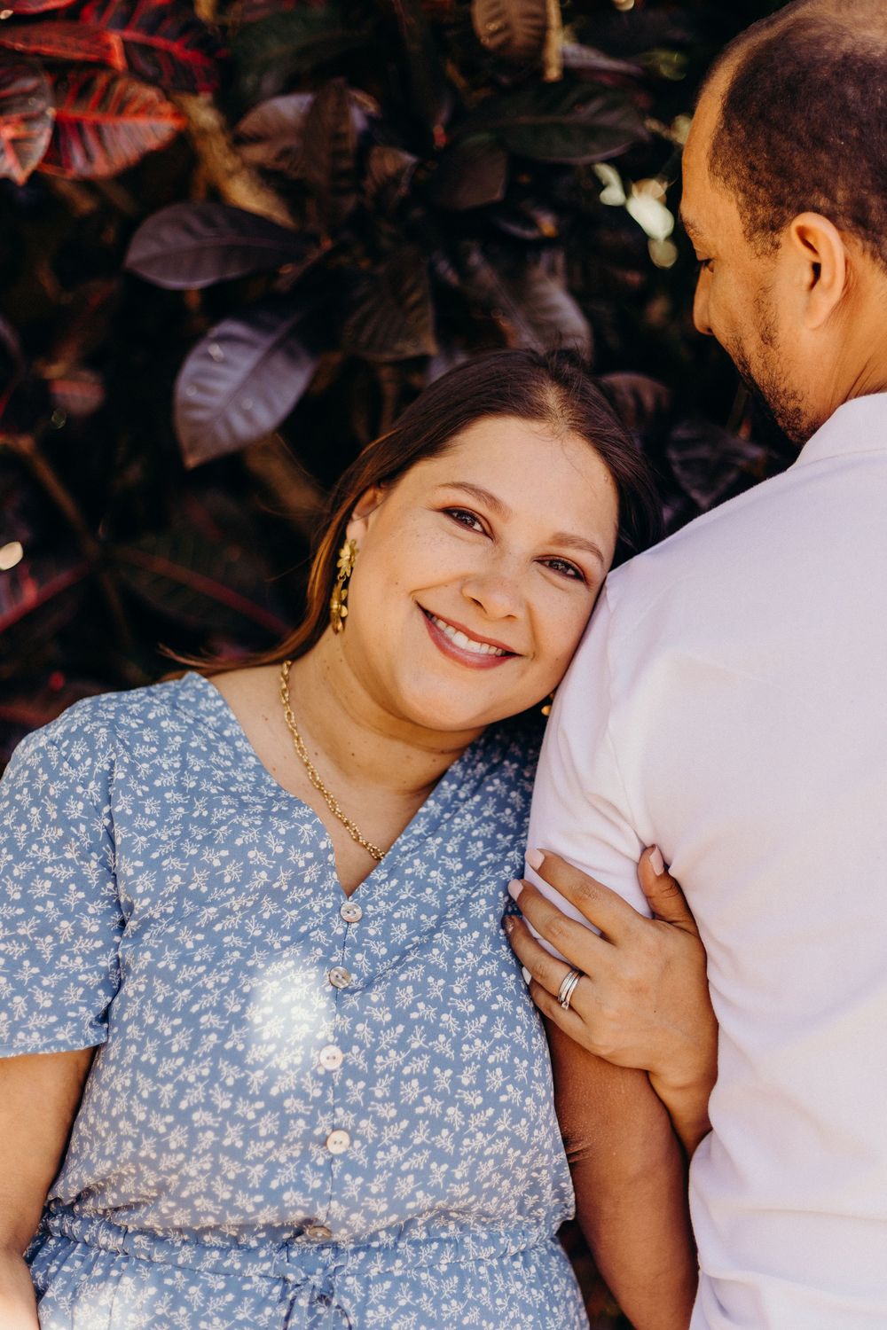 A couple shares an intimate moment against a backdrop of red leaves.