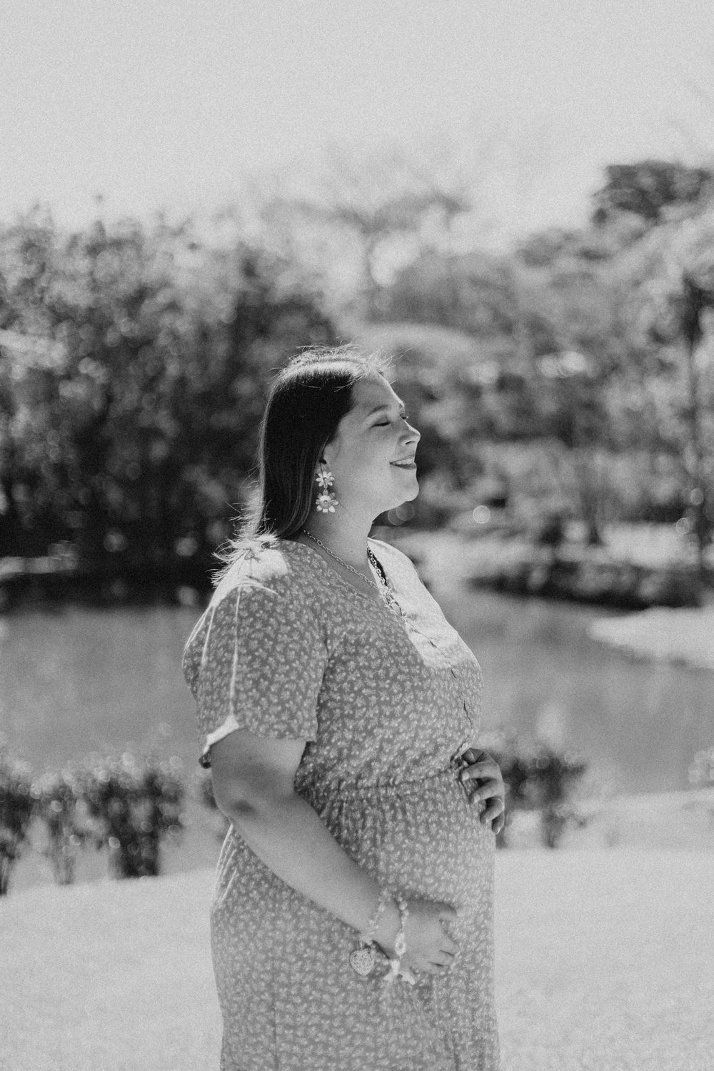 Black and white photo series of a woman in a polka dot dress joyfully twirling outdoors by a lake.