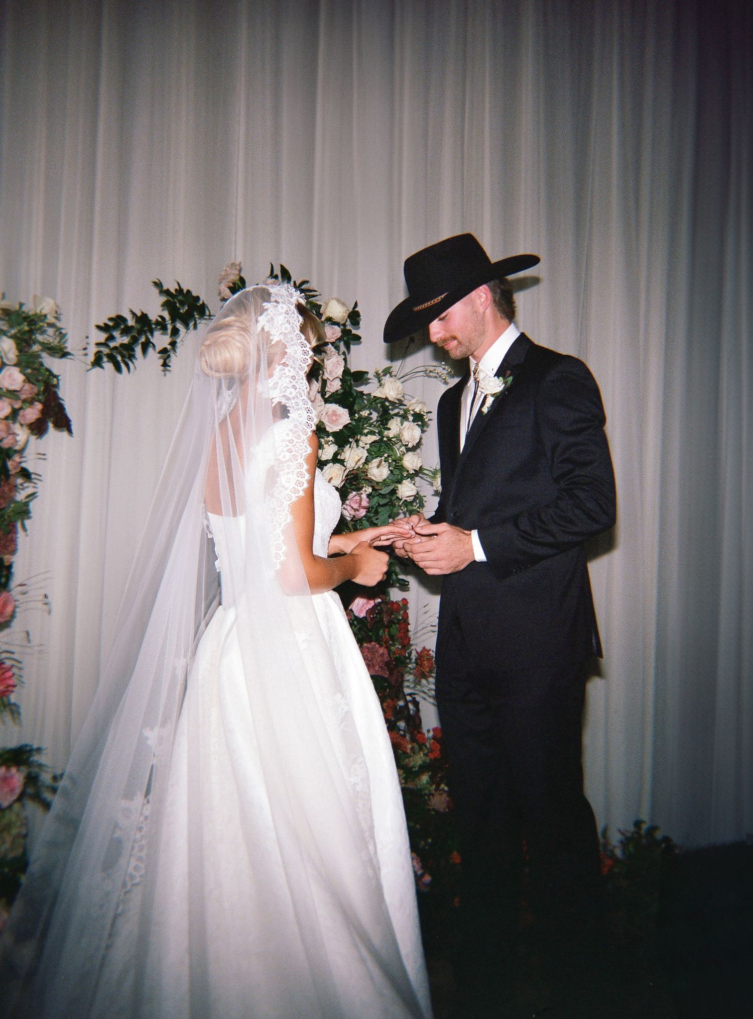 A wedding couple dances together in a series of four romantic black and white photos with white curtain backdrop.