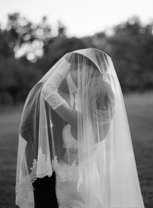 A romantic black and white wedding photo series showing a couple embracing under a delicate lace veil.
