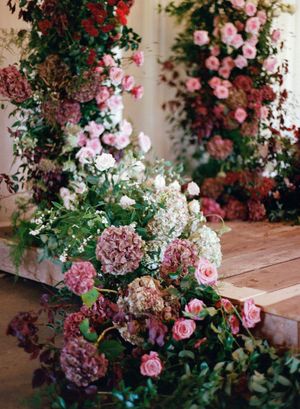 Pink and red roses with green foliage cascade down wooden steps in a romantic garden setting.