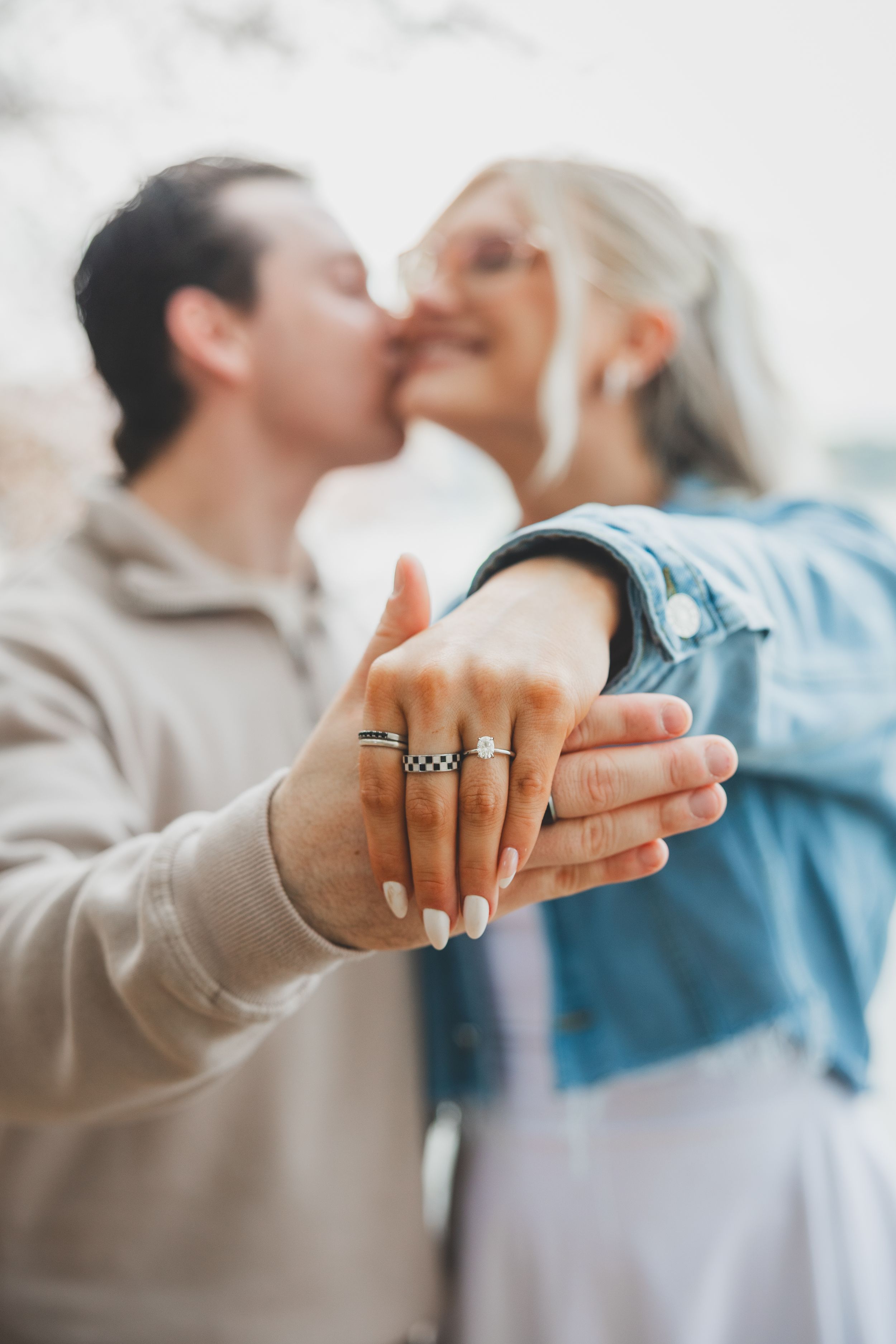 Close-up sequence of hands showing an engagement ring with couple kissing in soft focus background.