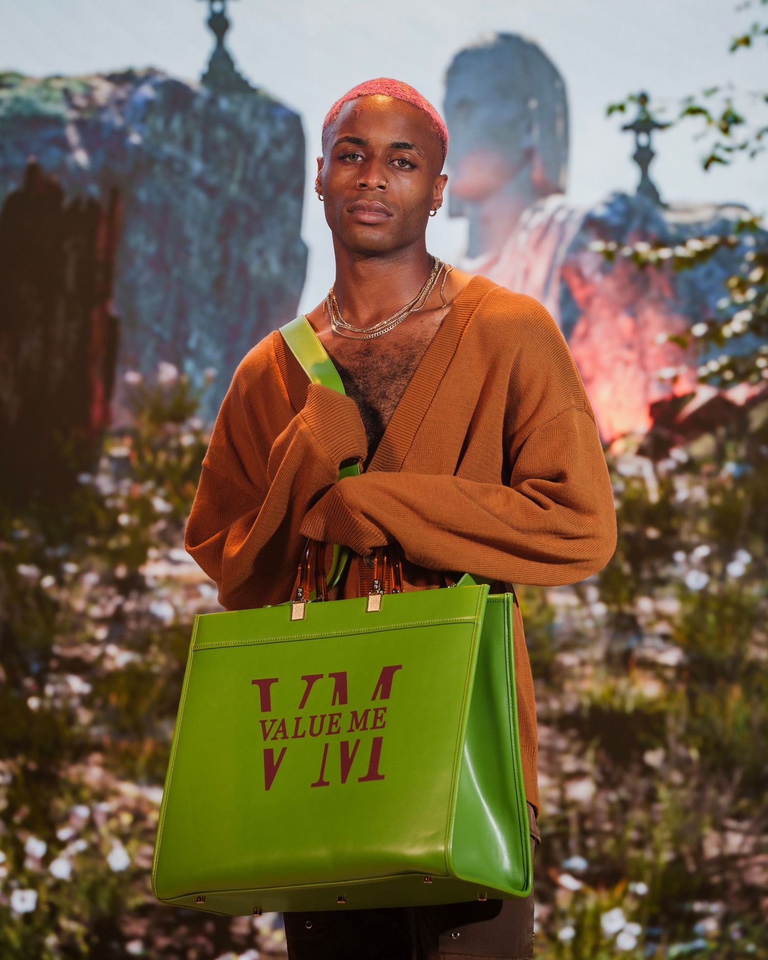 African American man rocking an orange sweater and green bag with burgundy letters saying Value Me.