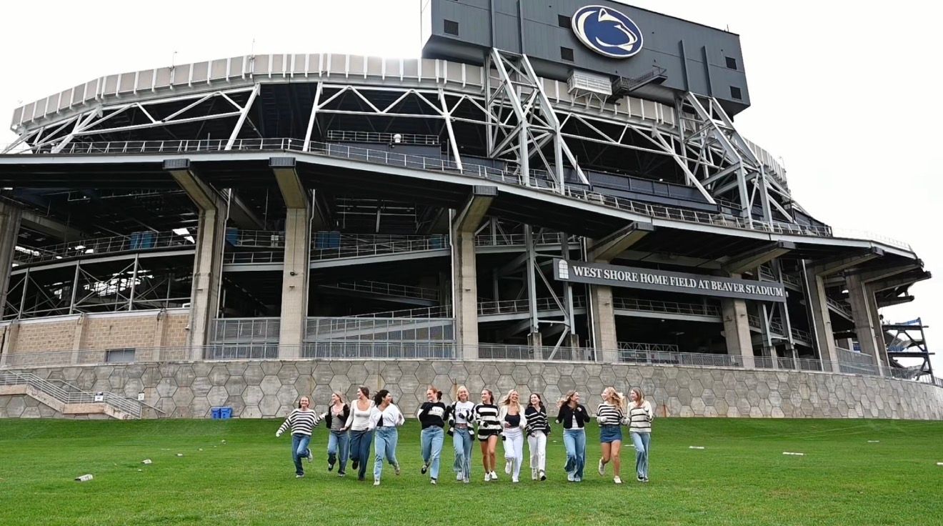 A group of people stand in front of the demolished Beaver Stadium at Penn State University.