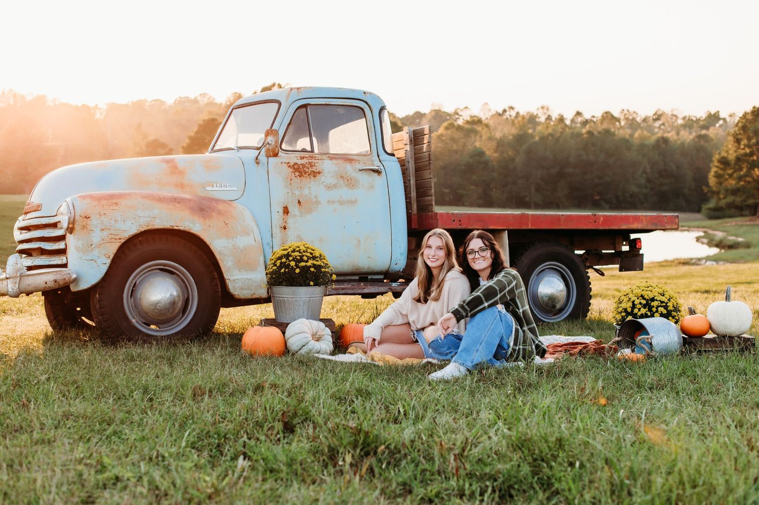 A rustic vintage pickup truck in a golden field at sunset serves as a backdrop for a cozy outdoor scene.