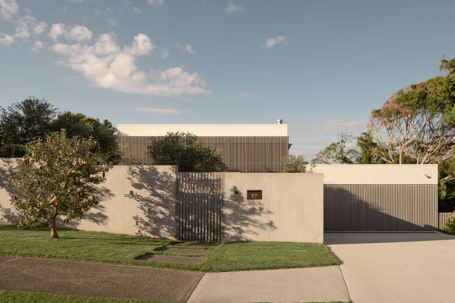 Modern commercial building exterior with sleek design and minimalist architecture against blue sky with scattered clouds.