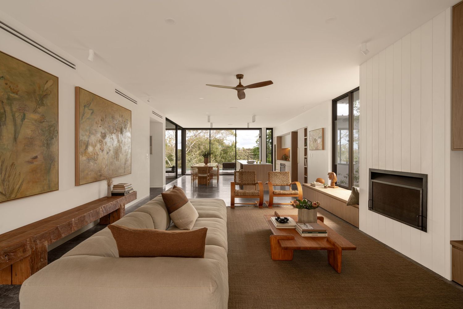 Modern living room with floor-to-ceiling windows, brown leather seating, and white fireplace in an open-concept space.