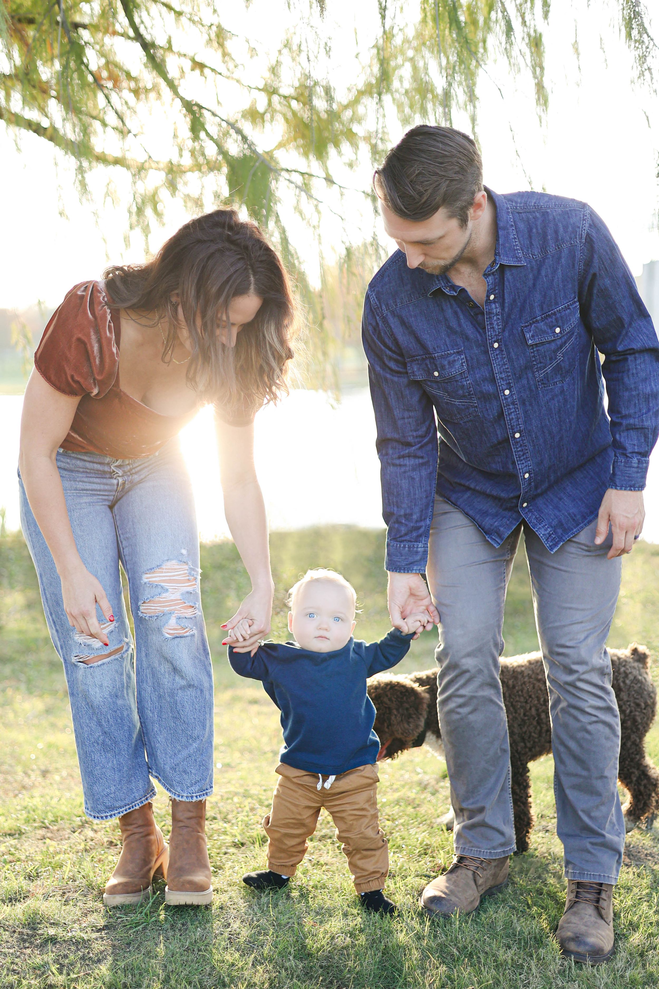 Mom and dad teach son how to walk in park.