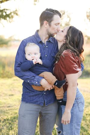 Family of three, mom and dad kissing.