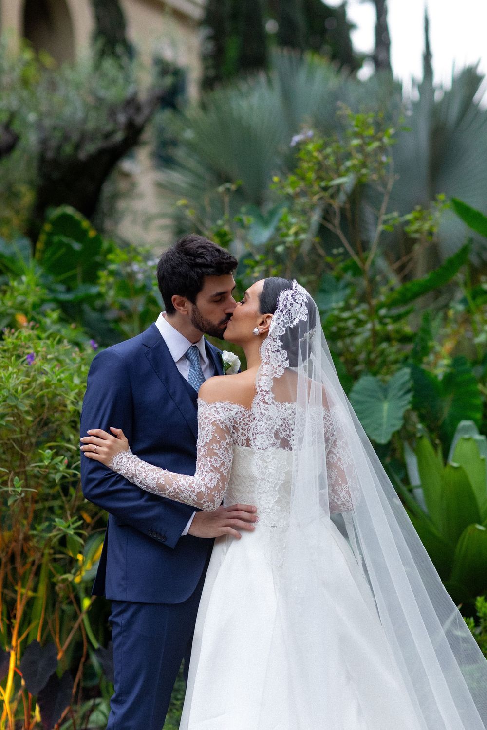 Romantic garden wedding moment with lush tropical plants in the background.