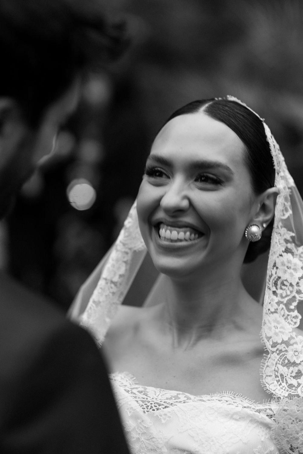 A black and white photo series shows a bride in a lace wedding dress smiling joyfully at different angles.