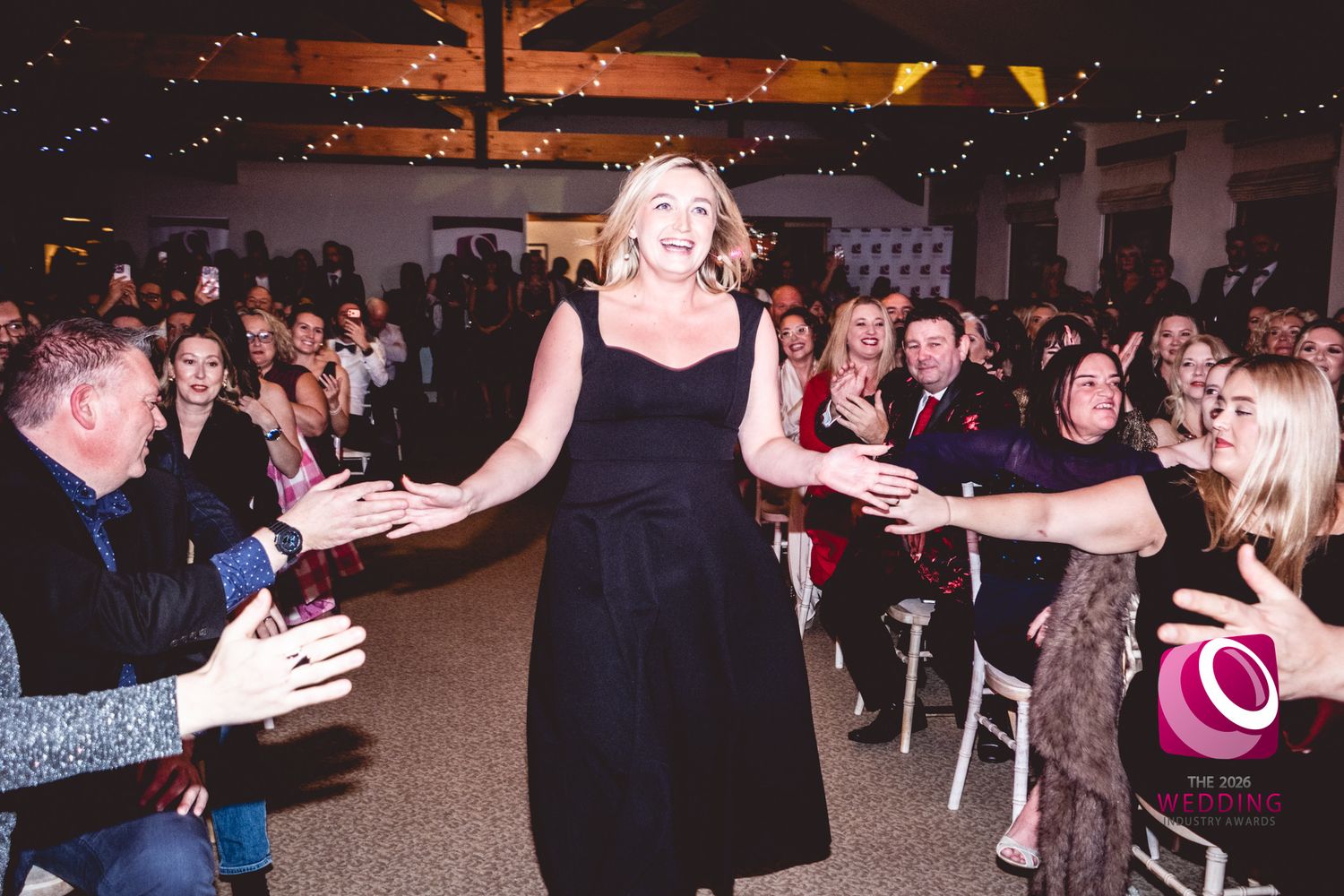 Wedding guests dancing and celebrating together on a dimly lit dance floor at a reception party.
