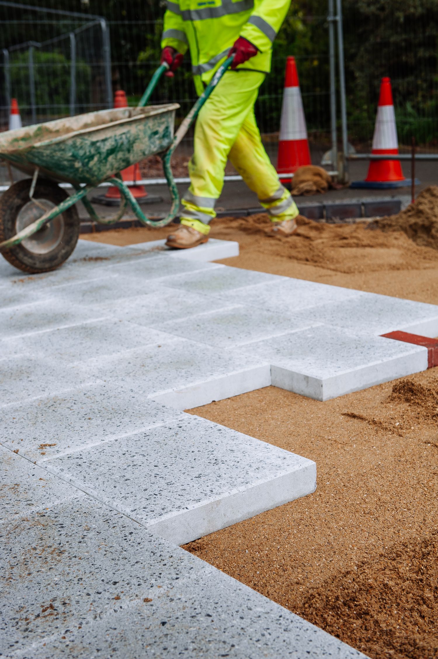 Step by step installation of concrete pavers showing progression of work on construction site.