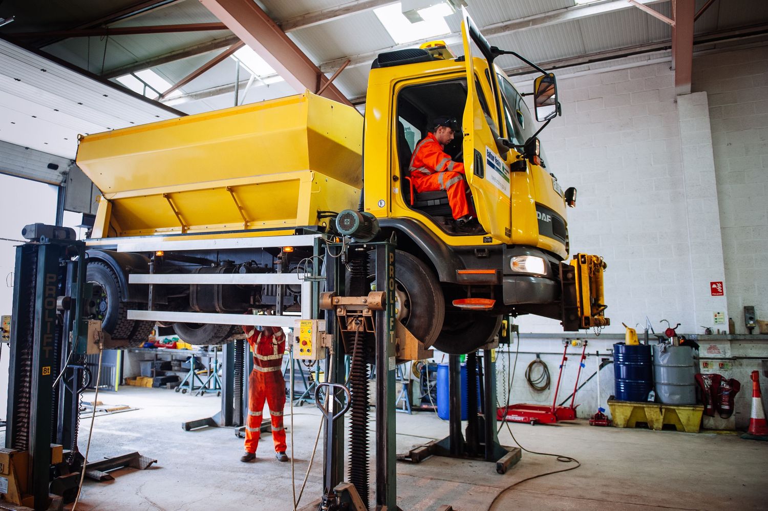 Large yellow construction vehicles and equipment inside an industrial warehouse facility.