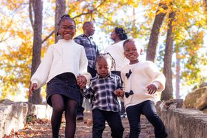 A group of children playing and laughing together outdoors during autumn with golden leaves in the background.