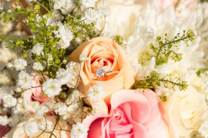 A delicate arrangement of peach and pink roses with white baby's breath flowers creates a romantic floral display.