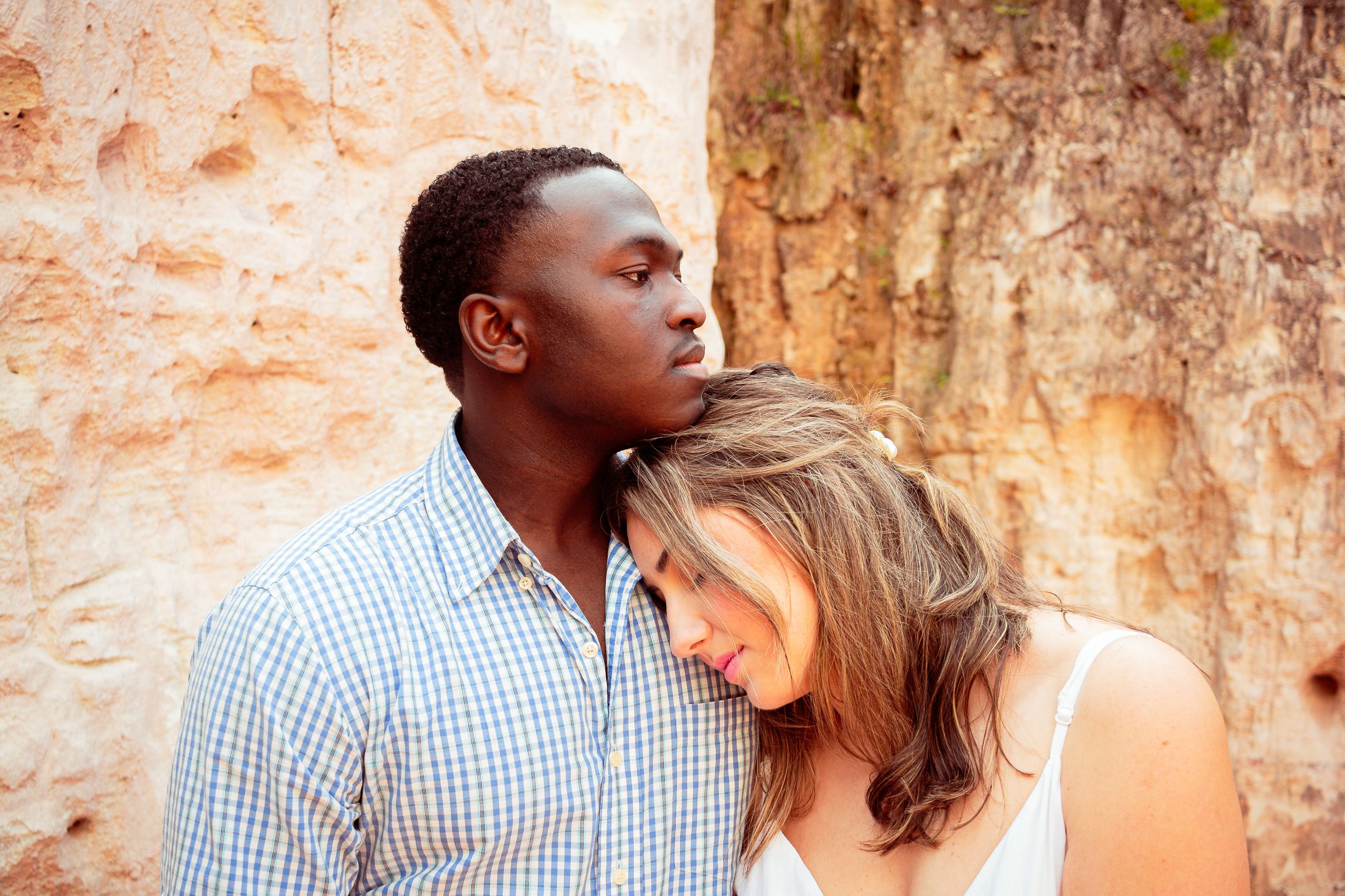 A couple shares tender moments against a rustic stone wall in a romantic outdoor photo session.