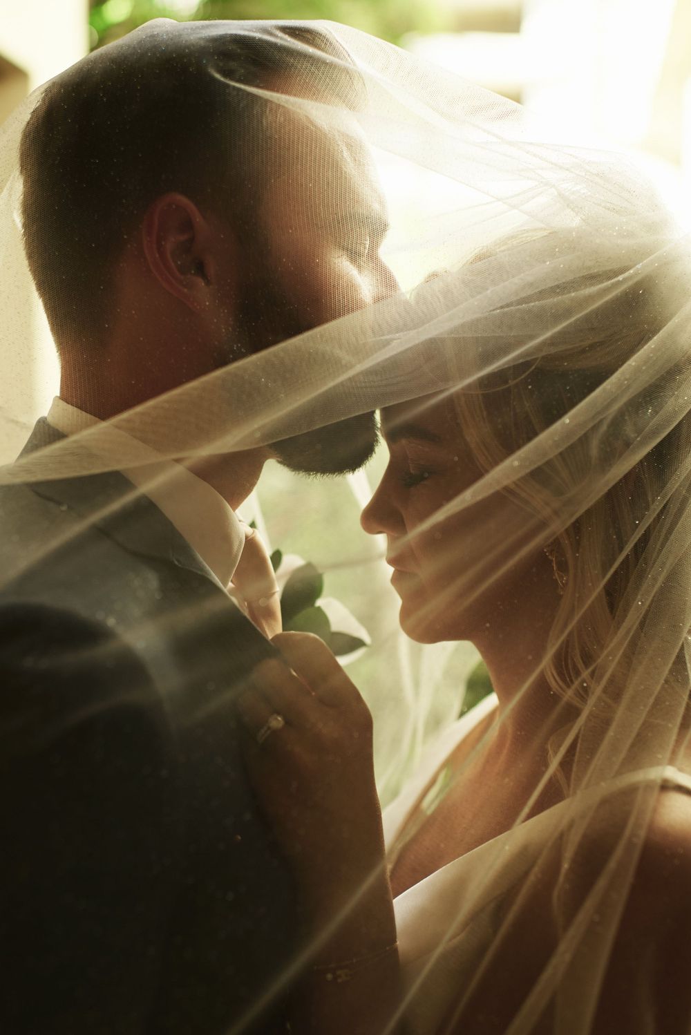 Romantic silhouettes beneath flowing wedding veil create dreamy atmosphere.