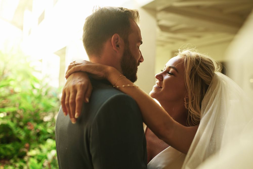 A romantic moment between newlyweds embracing in soft natural light.