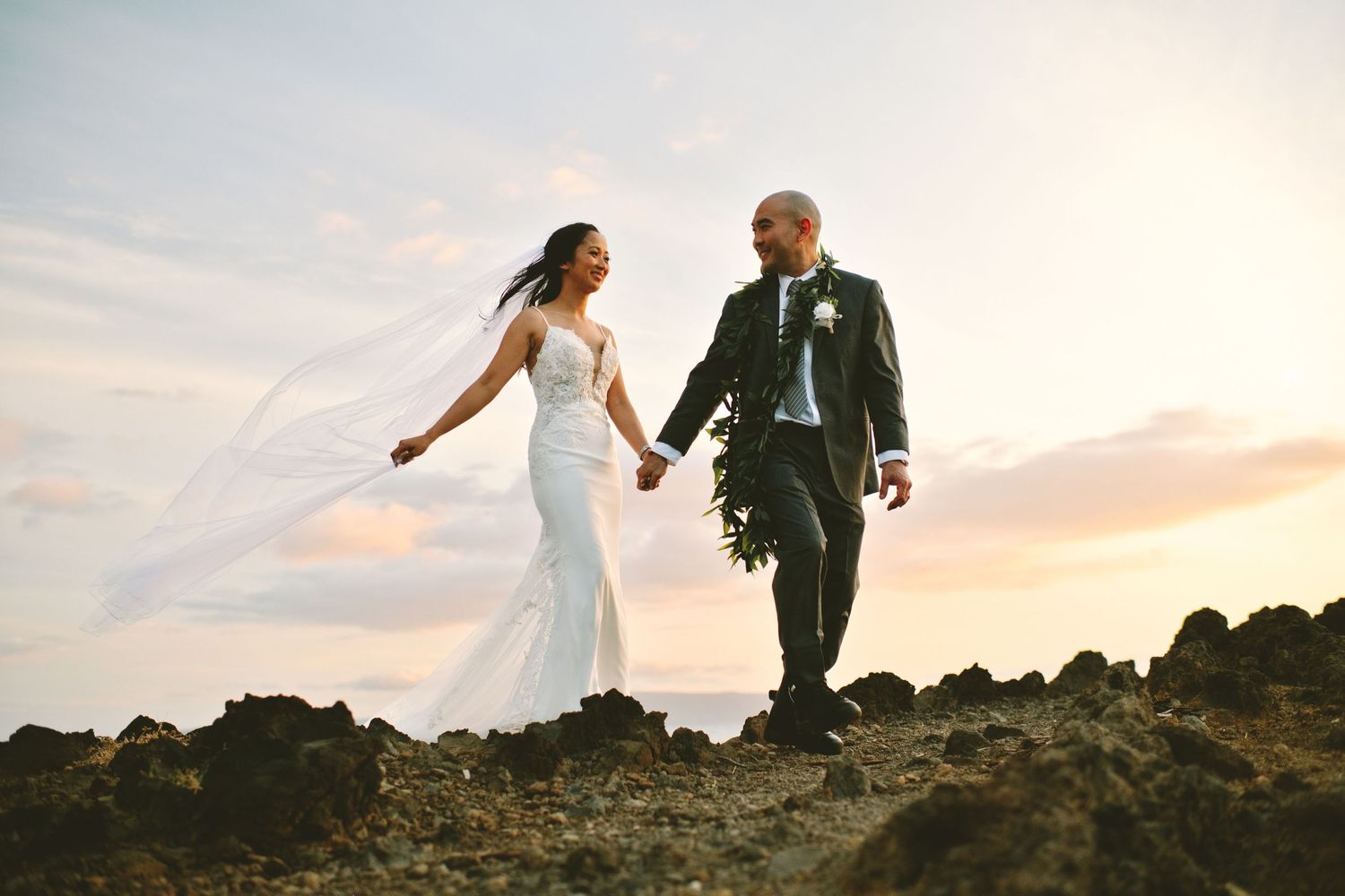 Bride and groom walking hand in hand at sunset at Kukahiko Estate on Maui