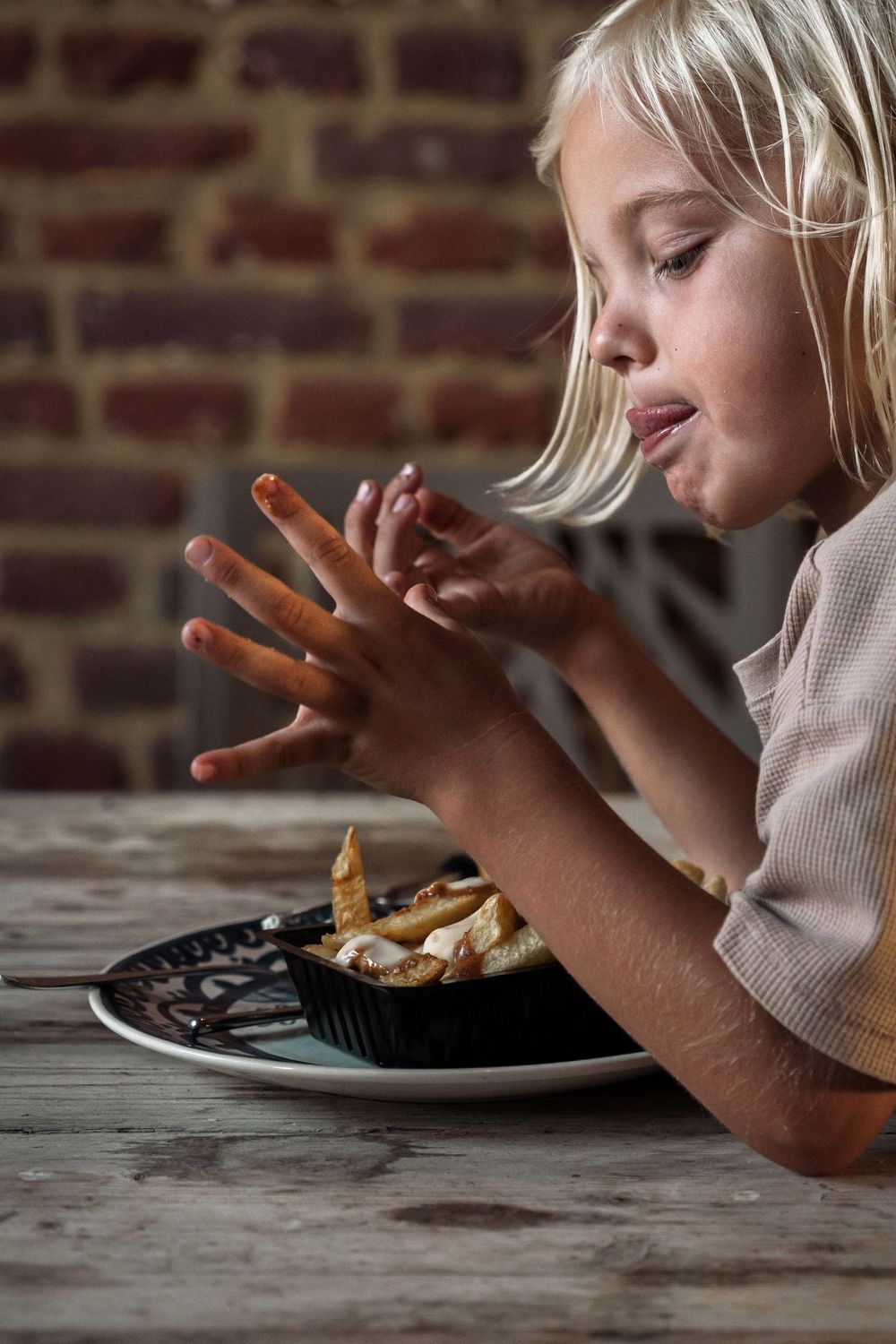 Close-up view of hands reaching for food on a rustic wooden table.
