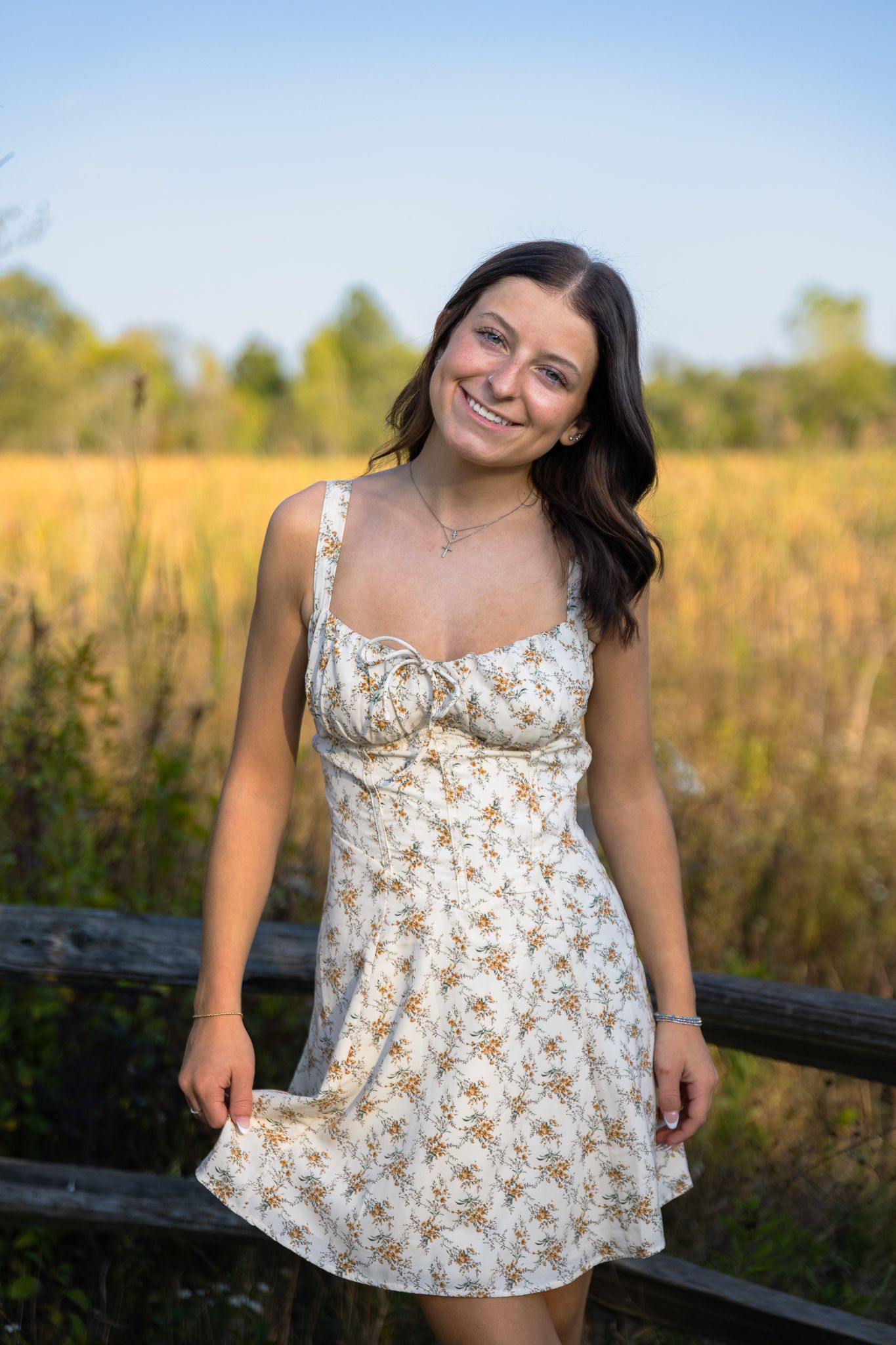 High school senior girl is smiling and posing in front of tall grass at Lillie Park South