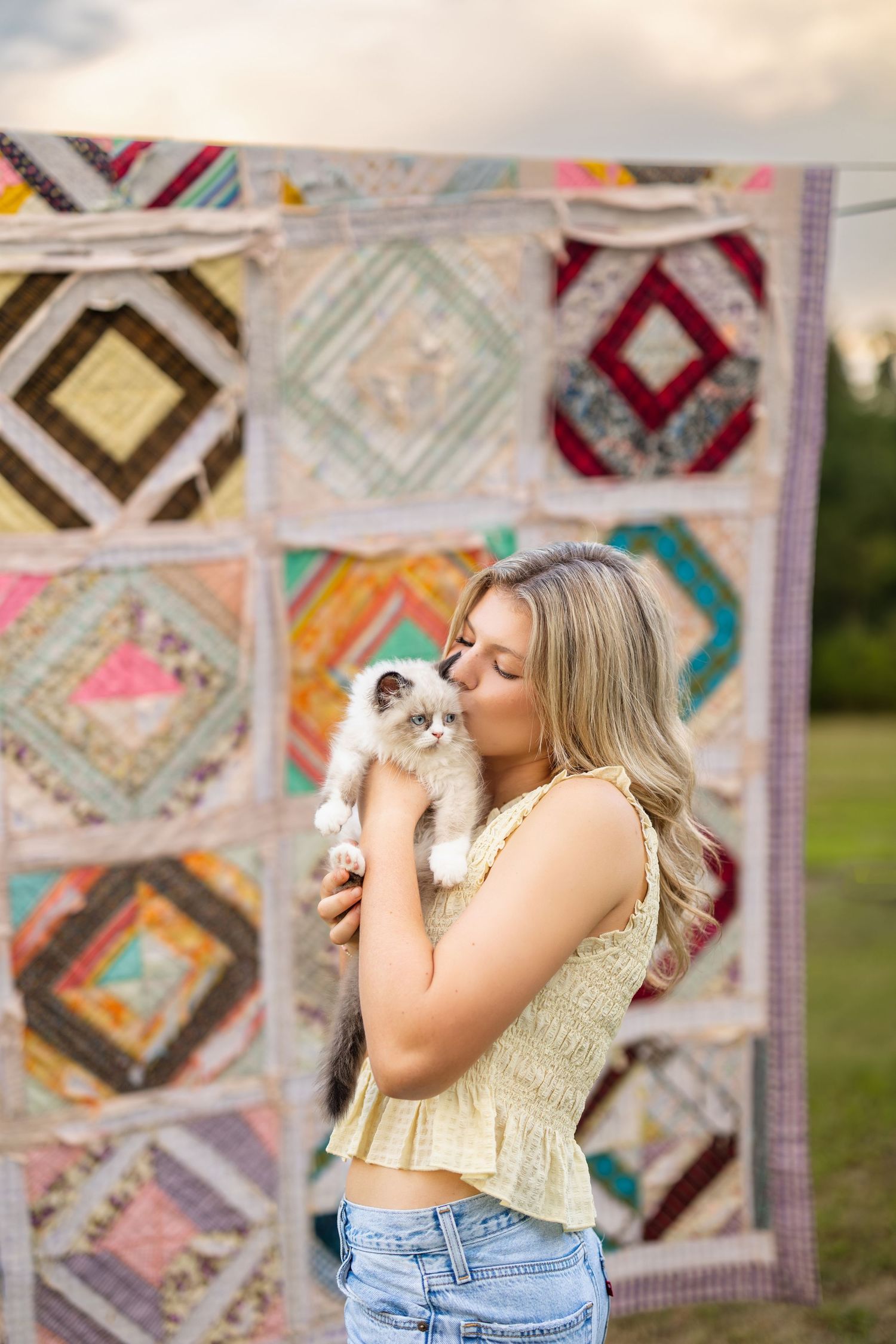 A sweet moment with a Ragdoll cat against a colorful patchwork quilt backdrop in an outdoor setting.