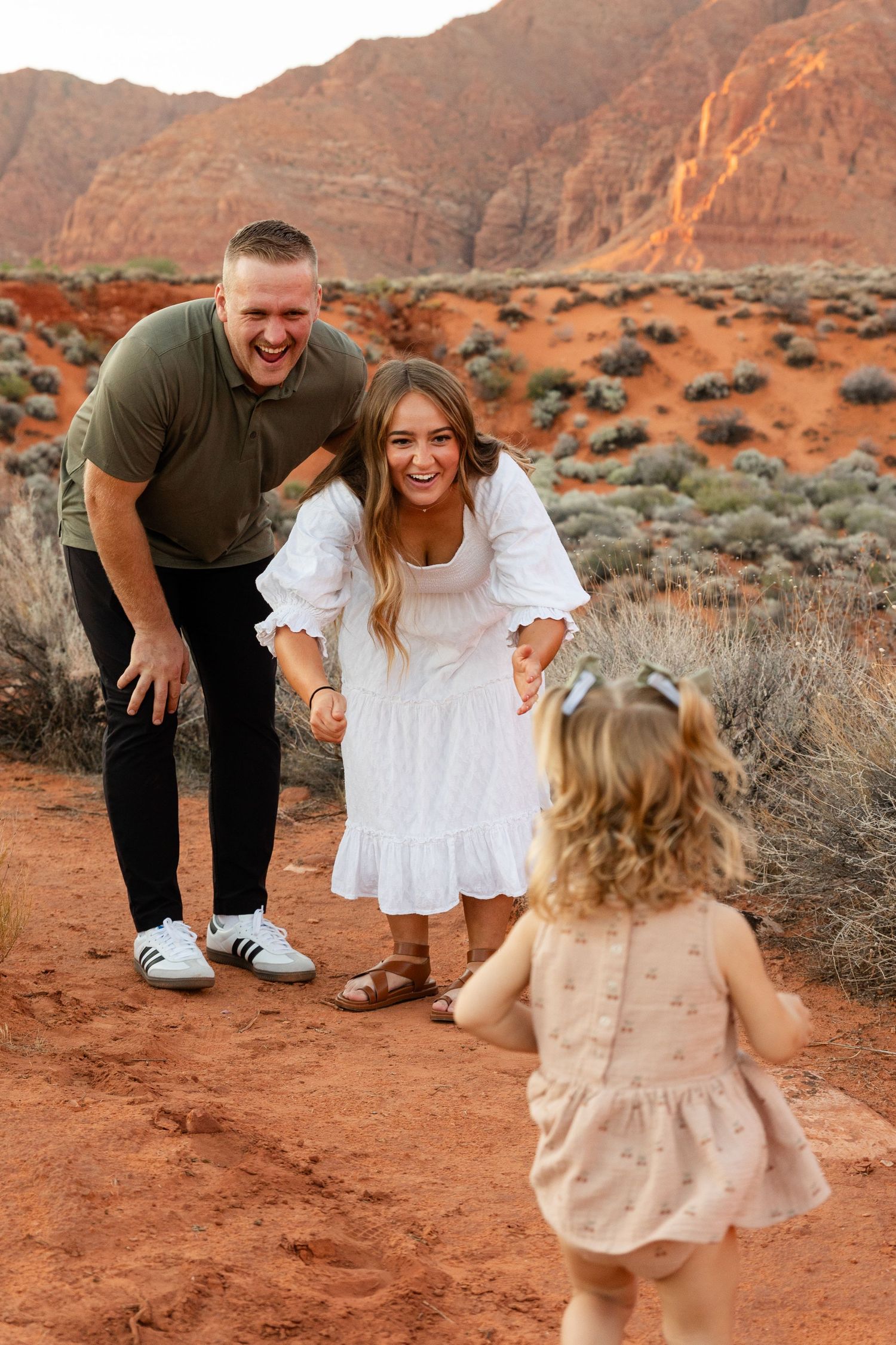 little girl running towards mom and dad in the red rock desert stunning back ground in southern utah