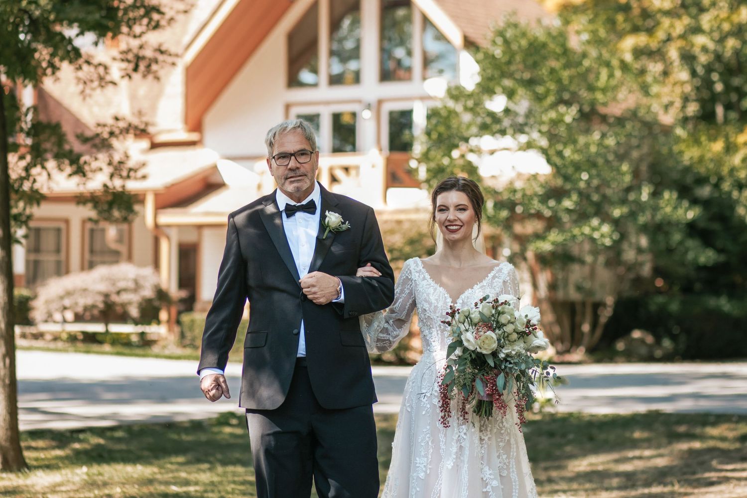 Wedding processional outside church with couple walking arm in arm carrying rustic bouquet.