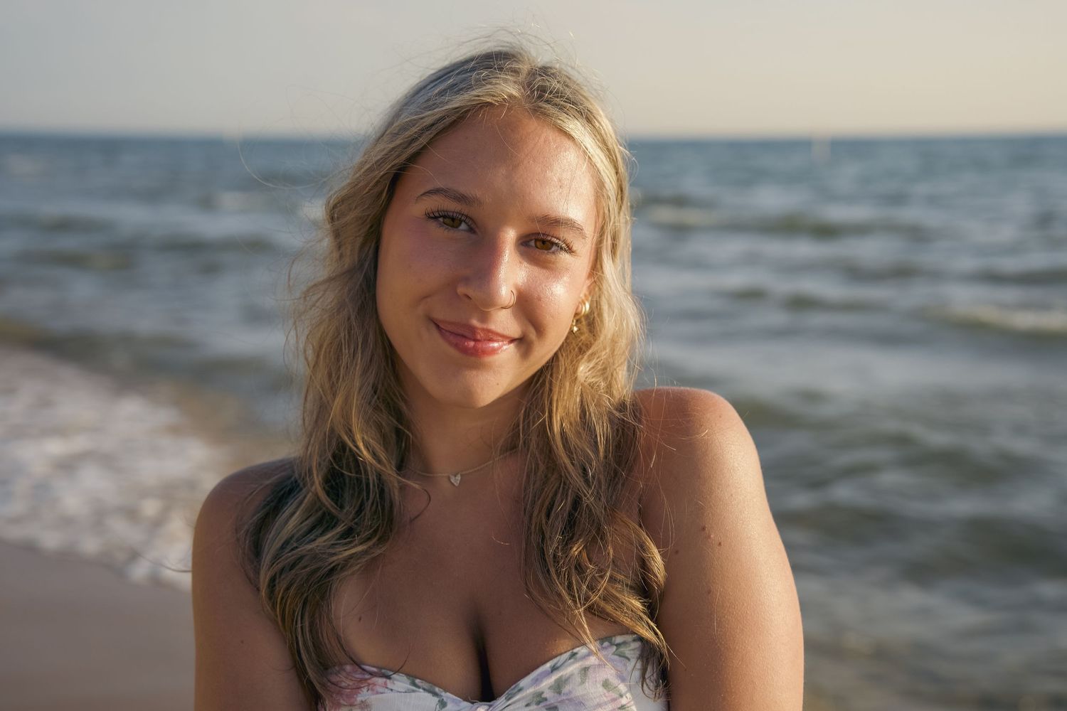 Woman enjoying a sunny day at the beach with waves crashing in the background.