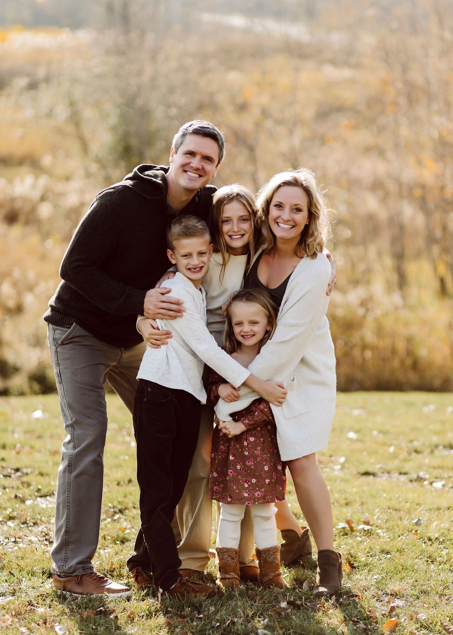 Family having fun together during an outdoor autumn photoshoot in a grassy field.