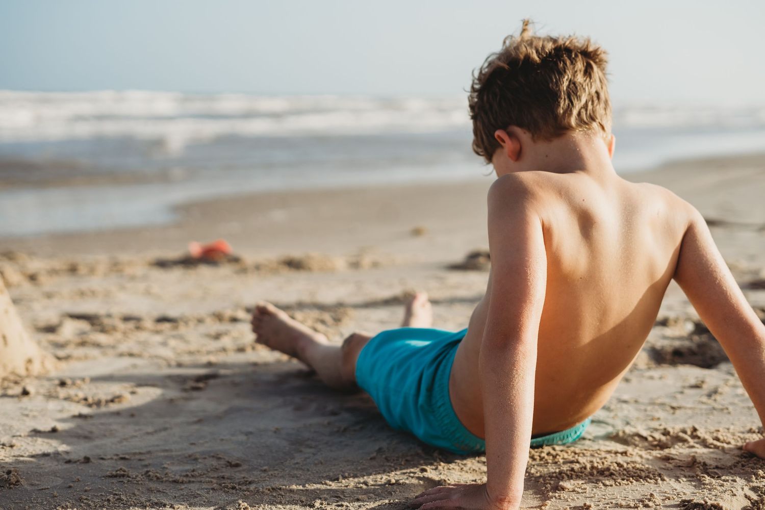 Young boy looking at the water at Matagorda Beach during a Matagorda Vacation Sunset Beach Photography Session.