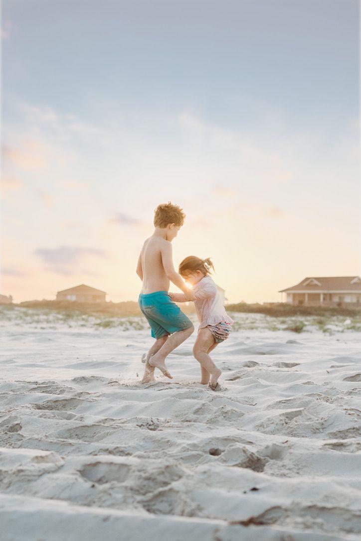 Two children holding hands and moving in a circle during an early morning vacation photography session at Matagorda Beach.