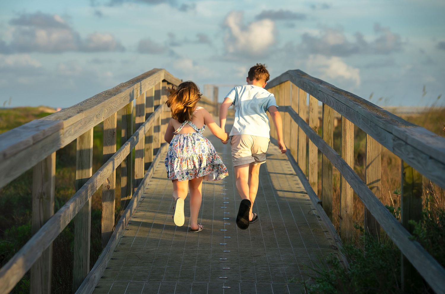 Two children running down the pier by the jetties in at Matagorda Beach during a Matagorda Vacation Sunset Beach photography session.