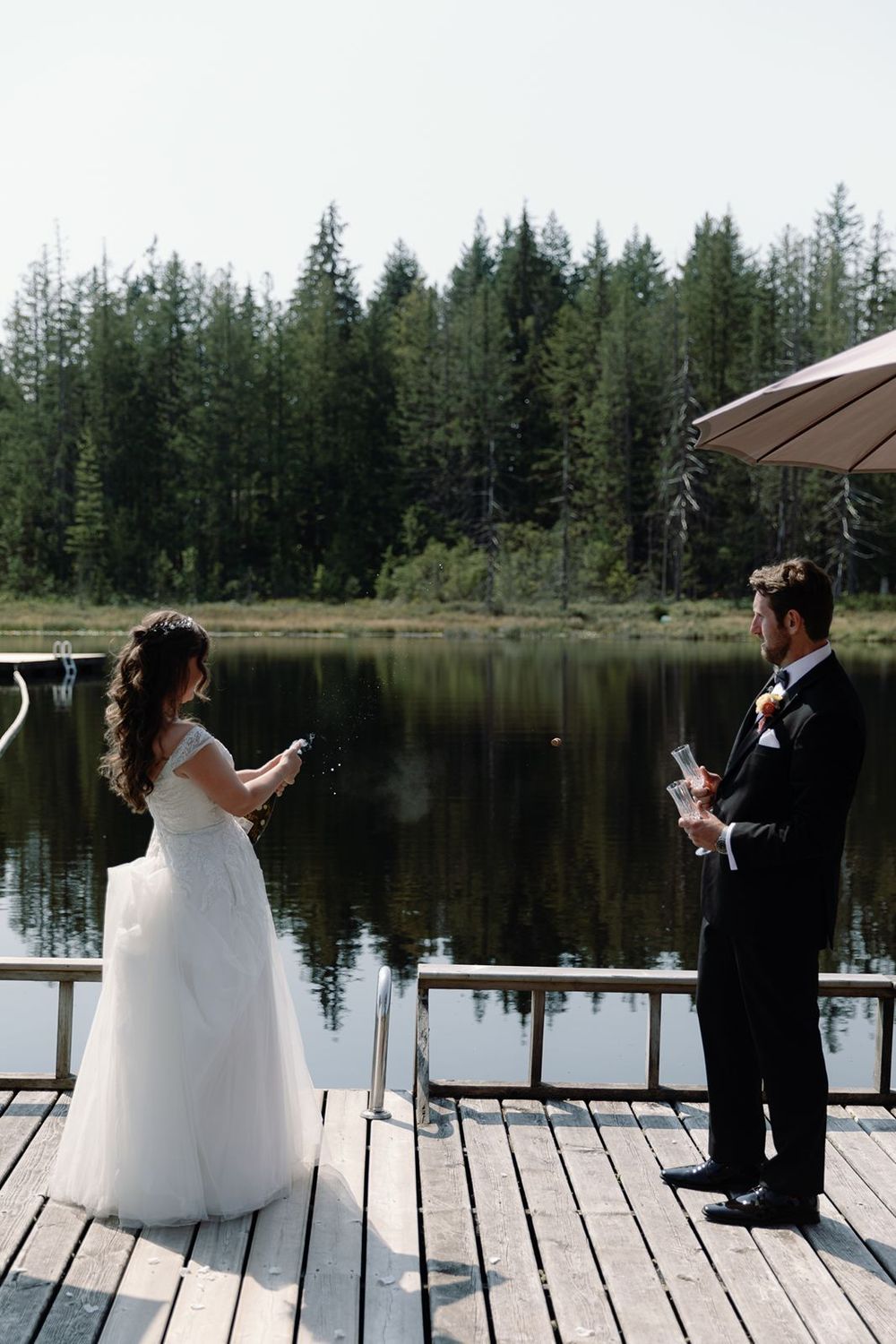 Couple popping a bottle of champagne on a dock during a Sunshine Coast wedding, laughter and sparkle.